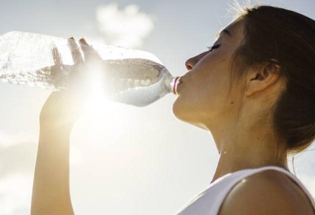 Mulher a beber água para hidratação da pele
