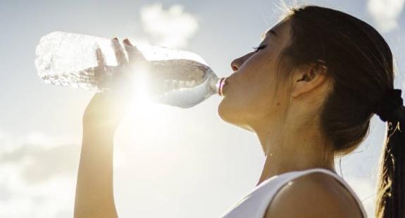 Mulher a beber água para hidratação da pele